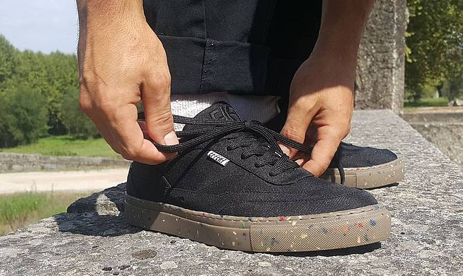 Mann bindet schwarzen Schuh aus Meeresplastik